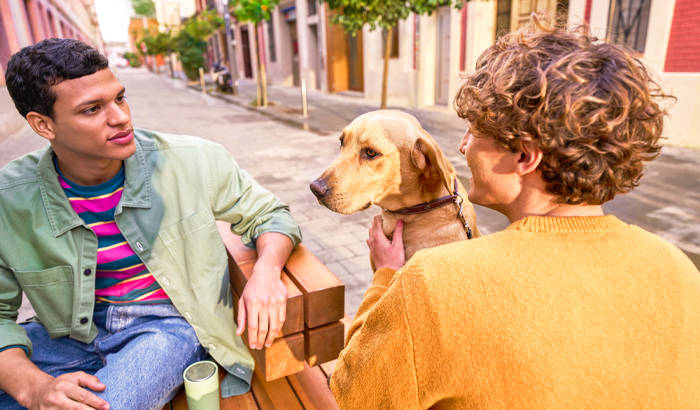 two men sitting and talking with dog